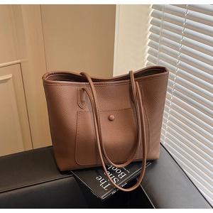 Close-up of brown litchi pattern leather tote bag with round buckle pocket and zipper