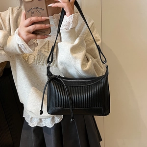 Minimalist black pleated underarm bag with silver hardware and leather fringe tassels
