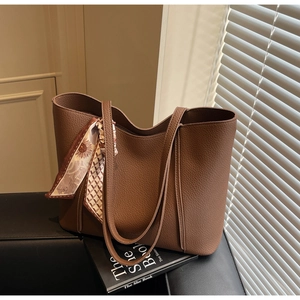 Detail of large brown pebble leather tote bag with elegant floral scarf on the handle