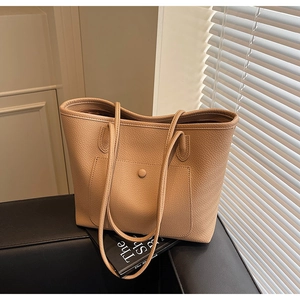 Close-up of beige tote bag showing high-quality lychee grain leather and front pocket