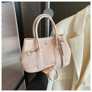 Detail of light pink pleated bucket bag with dual handles and adjustable shoulder strap