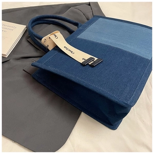 Detail view of contrast denim patchwork tote bag with stylish printed strap and sturdy handle