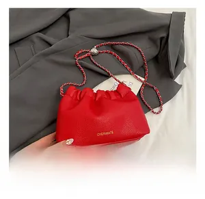 Close-up of red lychee grain leather on a ruffled cloud bag with golden logo detail