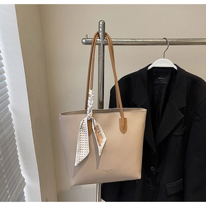 Detail of beige tote bag with a geometric print silk scarf wrapped on the handle