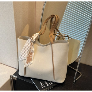 Detail of off-white lychee leather tote bag with brown straps and decorative silk scarf