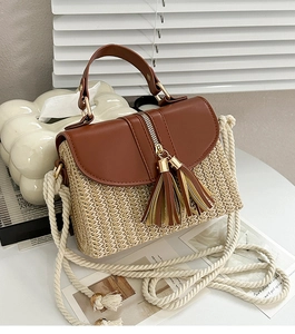 Détail du sac à main en paille avec rabat en cuir brun, glands et bandoulière corde