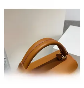 Detail of the brown leather top handle with refined stitching and gold hardware