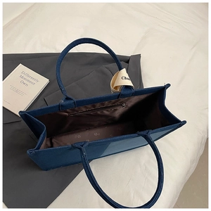 Detail view of denim tote bag with internal zipper pocket and white decorative ribbon