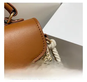Detail view of woven straw and brown leather handbag with metallic rings and stitching