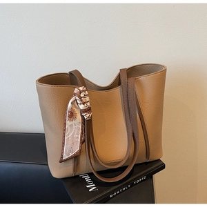 Detail of khaki tote bag featuring lychee grain leather texture and floral silk scarf