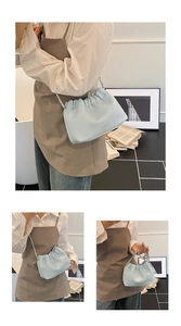 Close-up of light blue lychee pattern ruched cloud bag with silver chain strap and logo