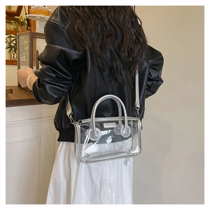 Transparente PVC-Tasche mit silbernem Lederbesatz, präsentiert von einem Model im Innenraum