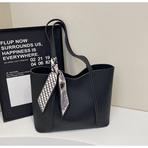 Close-up of black pebble leather tote bag with silk scarf detail on handle