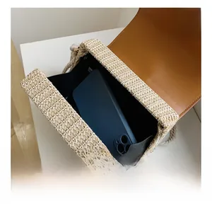 Close-up of woven straw crossbody bag interior showing storage capacity with a phone