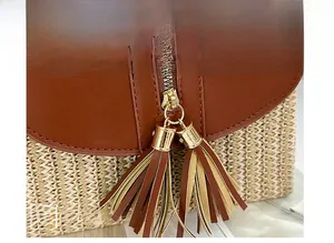 Détail du sac en paille avec fermeture éclair en métal et deux glands en cuir marron
