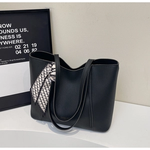 Detail of black lychee leather tote bag featuring elegant geometric print silk scarf handle