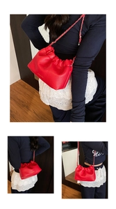 Detail of red ruched cloud bag with lychee texture and gold-tone chain strap