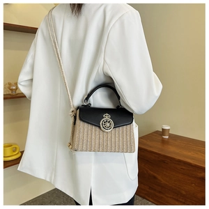 Detail of woven straw box bag with black leather flap and thick rope shoulder strap