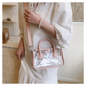 Detail der rosa transparenten PVC-Gelee-Tasche mit breitem Stoffgurt auf Spitzenkleid