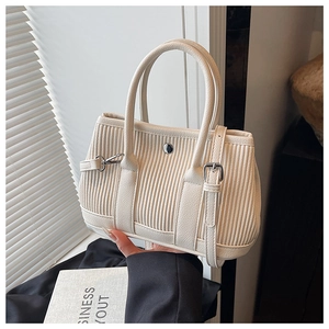 Close-up of pleated beige bucket bag showing striped texture and round metal lock detail