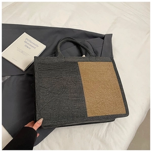 Detail of large canvas tote bag showing dark grey and khaki color block and textured fabric