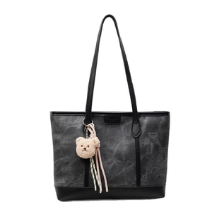Charcoal canvas tote bag with black leather trim and cute bear pendant on white background