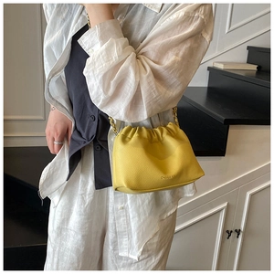 Detail of yellow pleated cloud bag featuring soft lychee texture and golden chain strap
