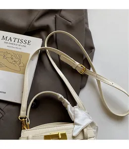 Détail d'un sac à main blanc crème avec motif crocodile, fermoir doré et foulard en soie