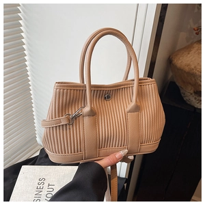 Detailed view of beige corduroy texture bucket bag with metallic buckle and shoulder strap