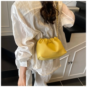 Close-up of bright yellow lychee leather bag with pleated design and chain strap