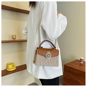 Detail of bohemian straw box bag featuring brown leather trim and golden crown clasp