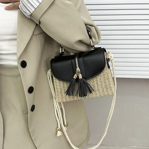 Detail of straw woven handbag with black leather flap and stylish tassel decorations