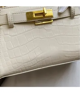 Gros plan sur la texture cuir crocodile blanc et le fermoir en métal doré