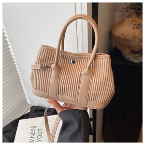 Detailed close-up of beige pleated bucket bag with silver metal ring and double handles