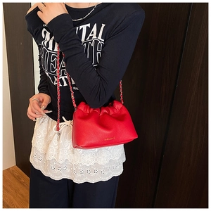 Detail of red lychee textured leather crossbody bag with gold logo and chain strap