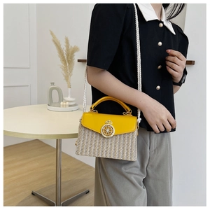 Detail of yellow straw woven box bag with golden helm buckle and white rope strap