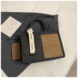Detail of dark grey felt tote bag with brown textured panel and cream ribbon accent