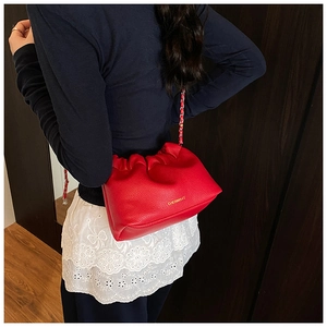 Detail of red lychee grain leather crossbody bag with pleated cloud design and chain strap
