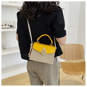 Detail of straw woven texture with yellow leather flap and golden crown lock on bag