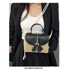 Détail du sac à main en paille tressée et cuir noir avec glands et accents dorés