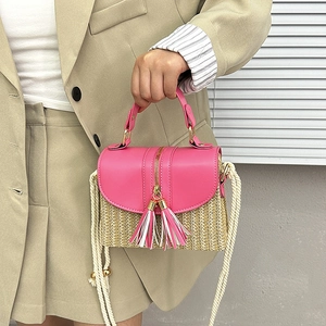 Detail of bohemian straw bag with pink leather trim, tassels, and cotton rope strap
