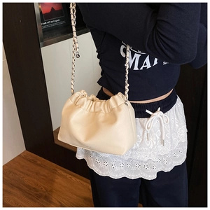 Close-up of beige ruched dumpling bag with litchi texture and leather chain strap