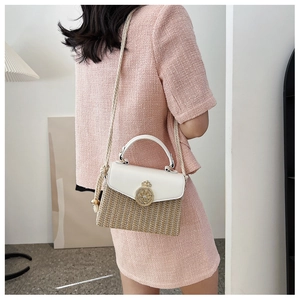 Detailed close-up of woven straw and leather box bag with gold crown lock buckle