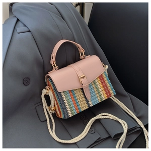 Détail du mini sac bandoulière tissé coloré avec rabat en cuir rose sur un blazer