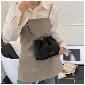 Close-up of black lychee texture leather crossbody bag with pleated drawstring and chain