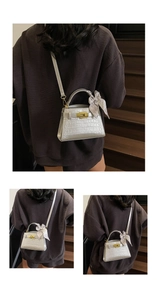 Détail du sac à main argenté à motif crocodile avec foulard en soie décoratif au manche