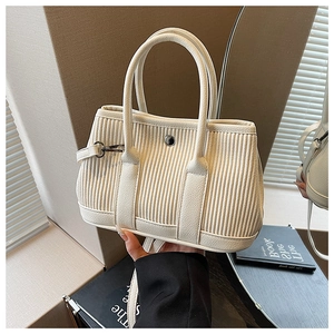 Detailed view of cream pleated bucket bag with vertical texture and silver metal buckle