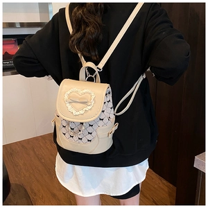 Detail of cream backpack featuring heart lace trim, ribbon bow, and check pattern accents