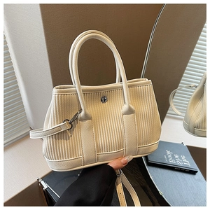 Detail of off-white corduroy tote with lychee leather base and decorative metal buckle
