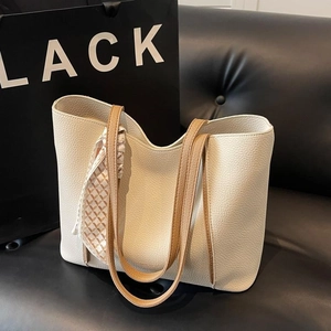 Minimalist beige lychee leather tote bag with brown straps and silk scarf on a sofa